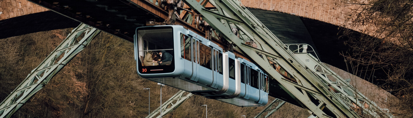 Das Bild zeigt die Schwebebahn bei der Fahrt durch Wuppertal.